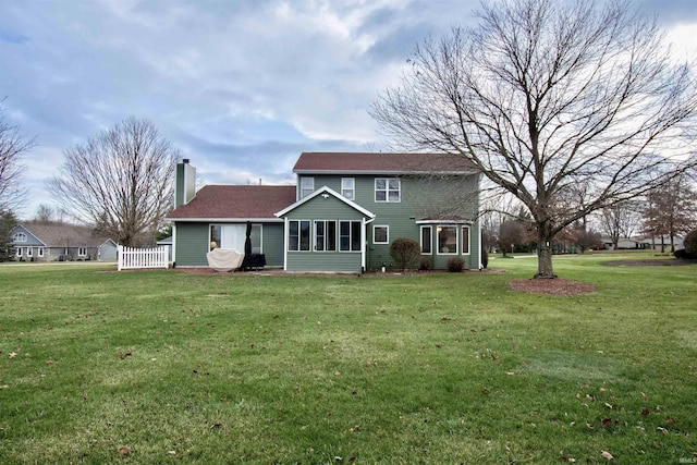 back of property with a sunroom and a lawn