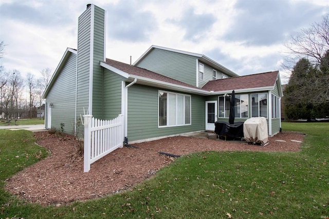 rear view of house featuring a yard and a sunroom