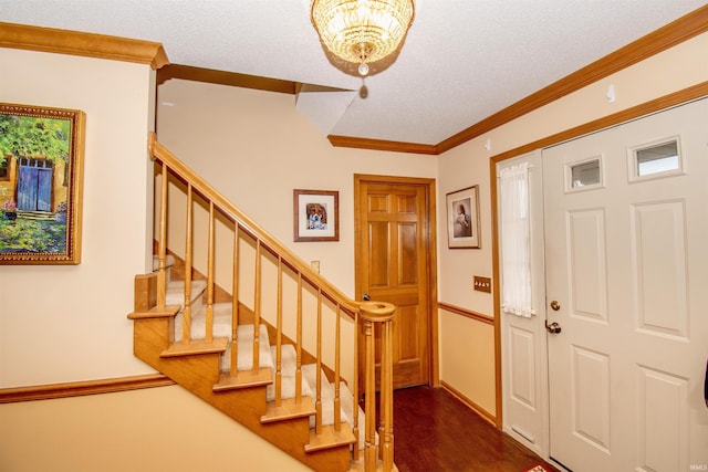 entrance foyer with a textured ceiling, dark hardwood / wood-style floors, an inviting chandelier, and ornamental molding