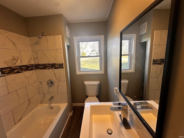 full bathroom with sink, toilet, hardwood / wood-style floors, and tiled shower / bath combo