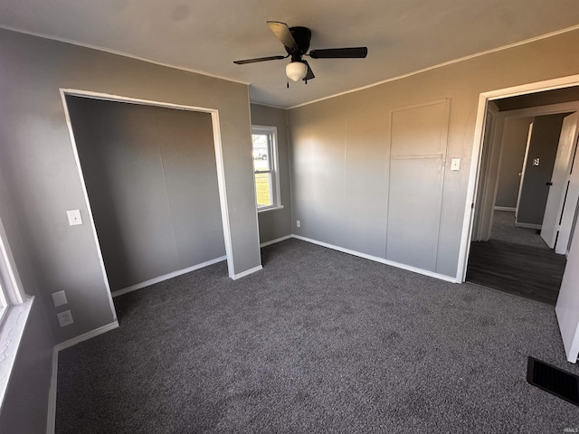 unfurnished bedroom with ceiling fan and dark carpet