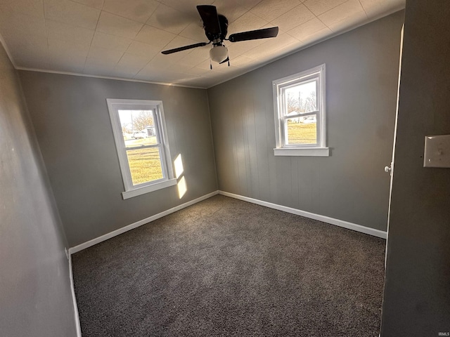 unfurnished room with ceiling fan, dark carpet, and a wealth of natural light