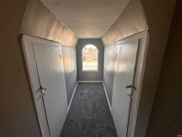 corridor featuring dark colored carpet and vaulted ceiling