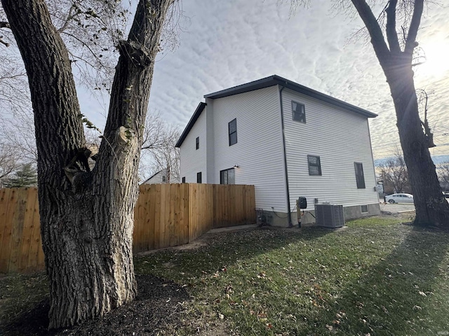 view of side of home with a yard and central AC