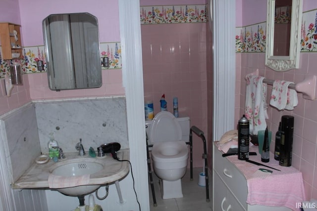 bathroom featuring tile patterned flooring, tile walls, and toilet