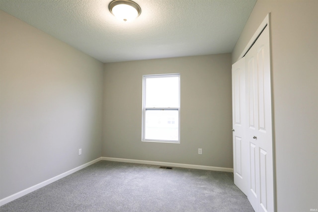 unfurnished bedroom with carpet floors, a textured ceiling, and a closet