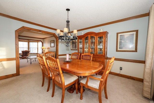 dining room featuring a chandelier, crown molding, light colored carpet, and a textured ceiling