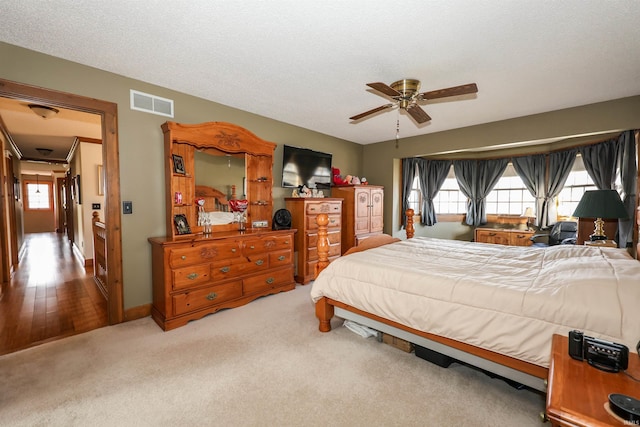 bedroom featuring ceiling fan, wood-type flooring, and a textured ceiling