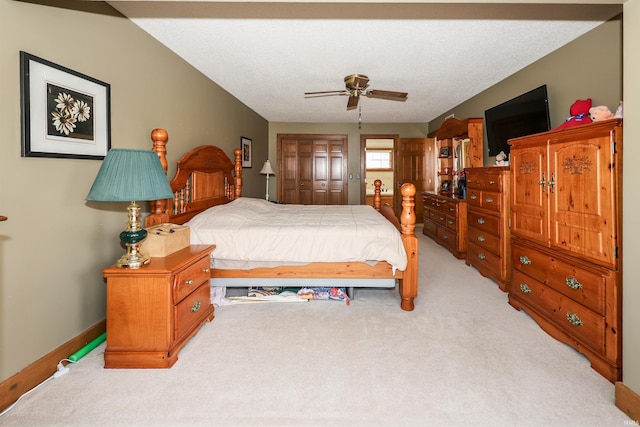 bedroom with ceiling fan, a closet, light colored carpet, and a textured ceiling