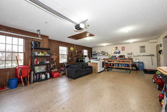 garage with a workshop area, a garage door opener, and wooden walls