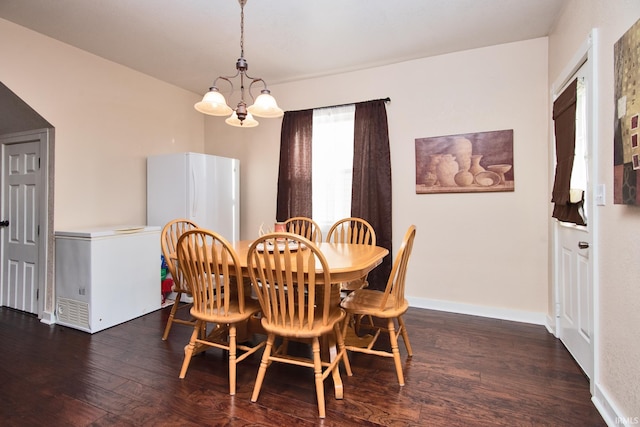 dining space with dark hardwood / wood-style flooring and an inviting chandelier