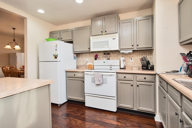 kitchen with backsplash, white appliances, dark wood-type flooring, decorative light fixtures, and a chandelier