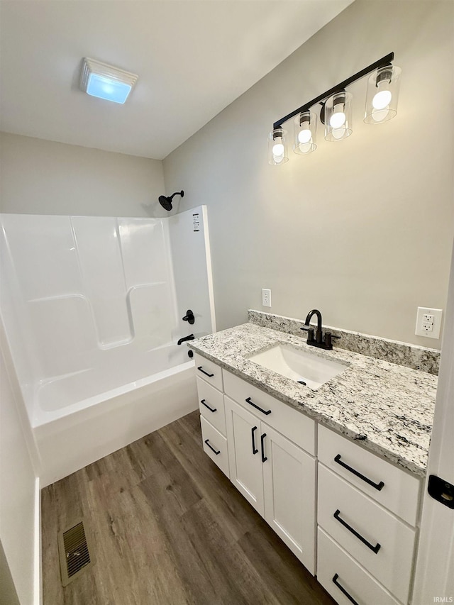 bathroom featuring hardwood / wood-style flooring, vanity, and shower / bathing tub combination