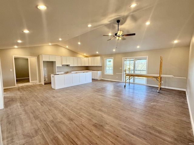 kitchen with white cabinetry, vaulted ceiling, a kitchen island, ceiling fan, and light hardwood / wood-style floors