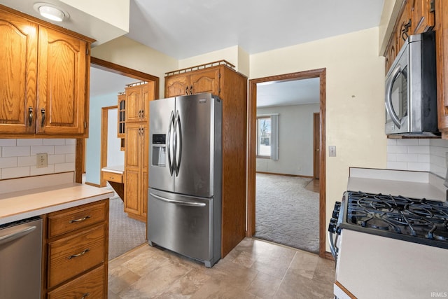 kitchen with decorative backsplash, light carpet, and appliances with stainless steel finishes