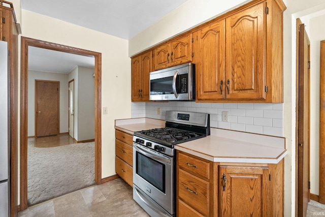 kitchen with light carpet, stainless steel appliances, and tasteful backsplash