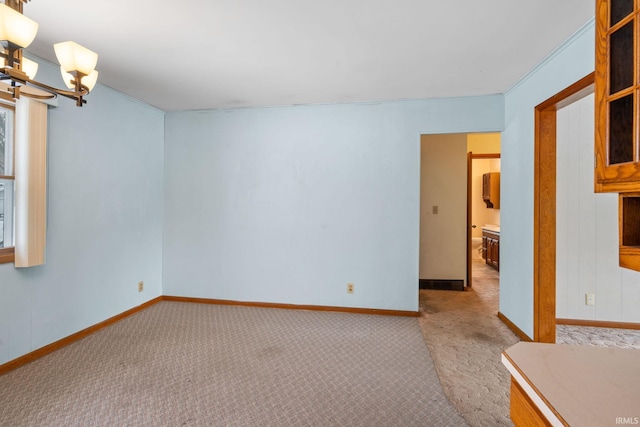 empty room featuring light colored carpet, ornamental molding, and an inviting chandelier