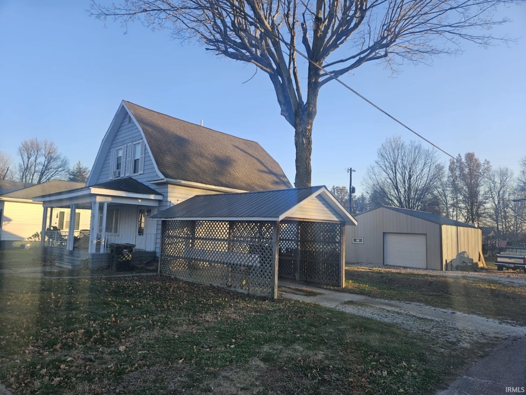 view of front of house with a front yard, a carport, a porch, an outbuilding, and a garage