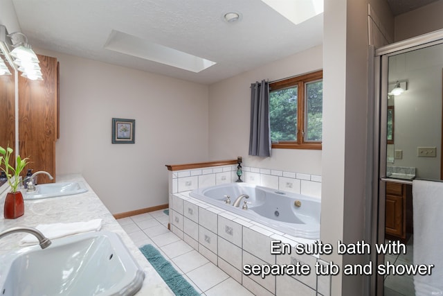 bathroom with tile patterned floors, a skylight, vanity, and a textured ceiling