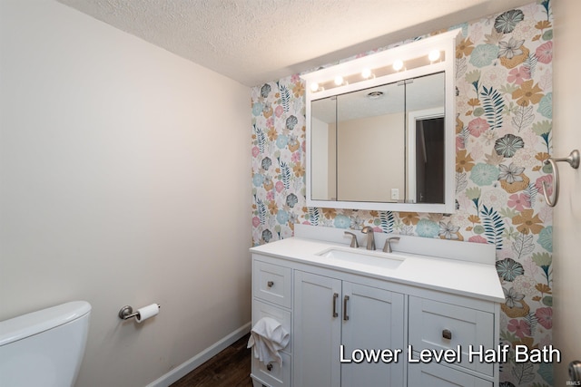 bathroom featuring hardwood / wood-style flooring, vanity, toilet, and a textured ceiling