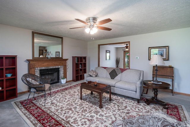 living room featuring ceiling fan, a textured ceiling, and a brick fireplace