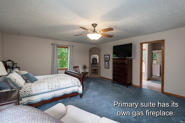 carpeted bedroom featuring a textured ceiling, ensuite bath, and ceiling fan