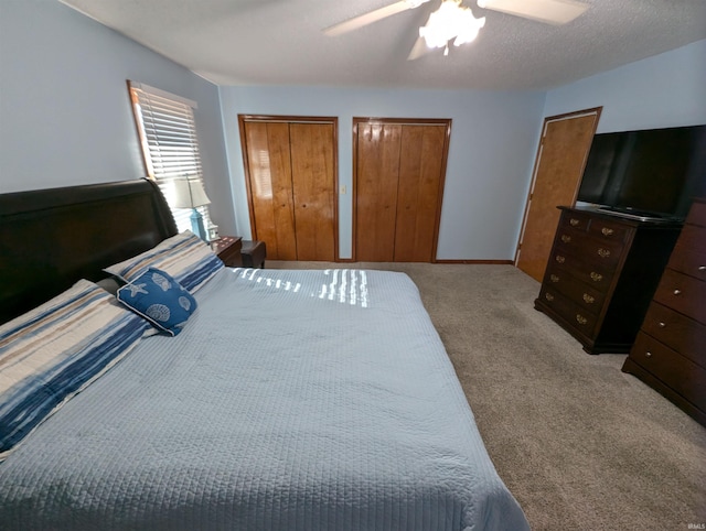 bedroom with light carpet, a textured ceiling, ceiling fan, and multiple closets