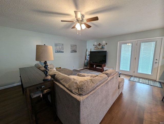 living room with a textured ceiling, ceiling fan, and dark wood-type flooring