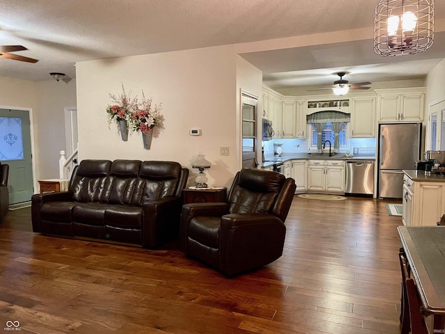 living room featuring dark hardwood / wood-style floors, a textured ceiling, and ceiling fan with notable chandelier