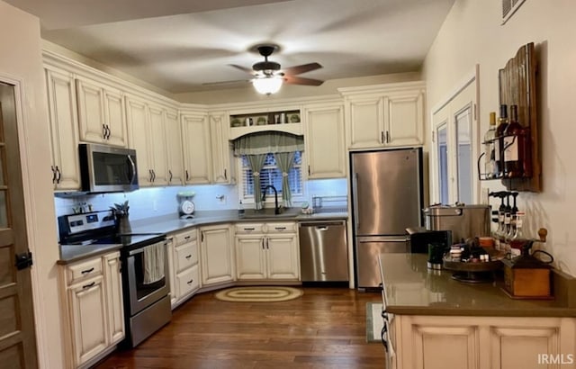 kitchen with sink, dark hardwood / wood-style floors, ceiling fan, cream cabinetry, and stainless steel appliances