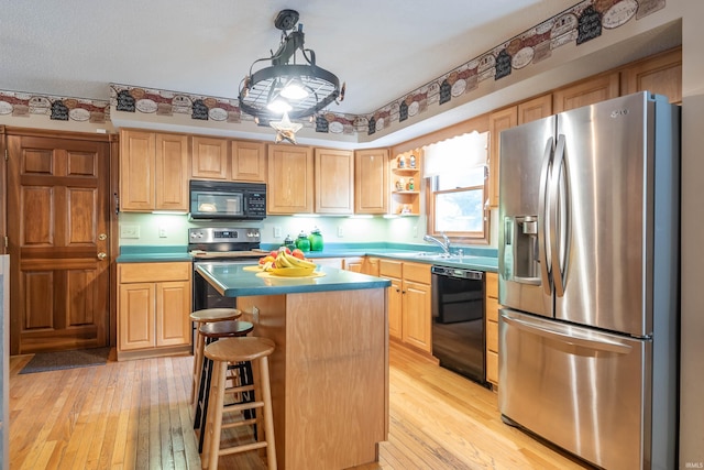 kitchen with pendant lighting, a center island, light hardwood / wood-style flooring, and black appliances