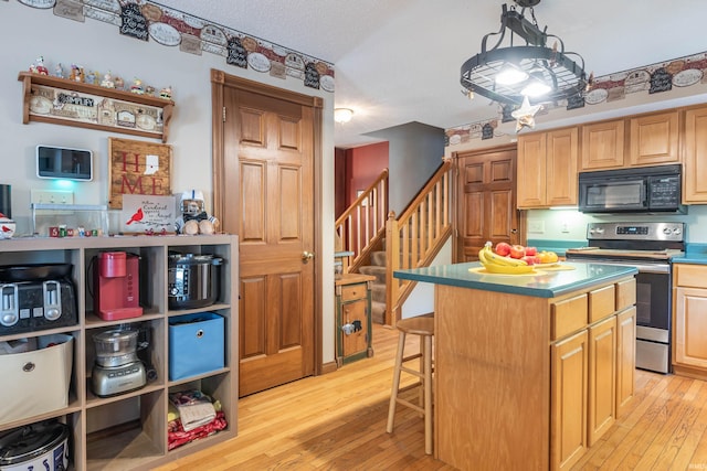 kitchen with stainless steel range with electric stovetop, a breakfast bar, a kitchen island, and light hardwood / wood-style floors