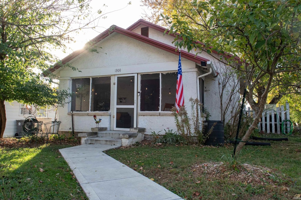 bungalow-style home featuring a sunroom and a front yard