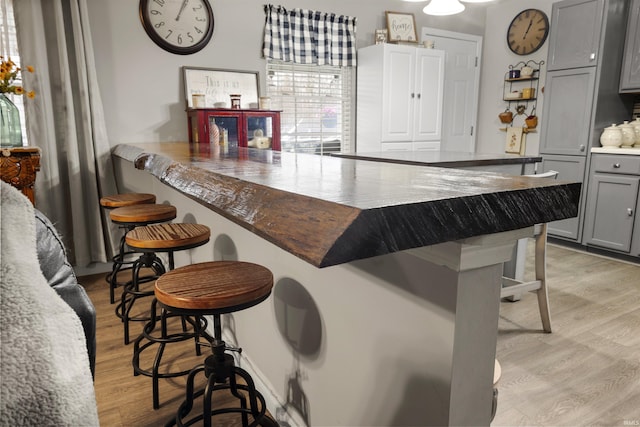 kitchen featuring a kitchen bar, light hardwood / wood-style flooring, and gray cabinetry