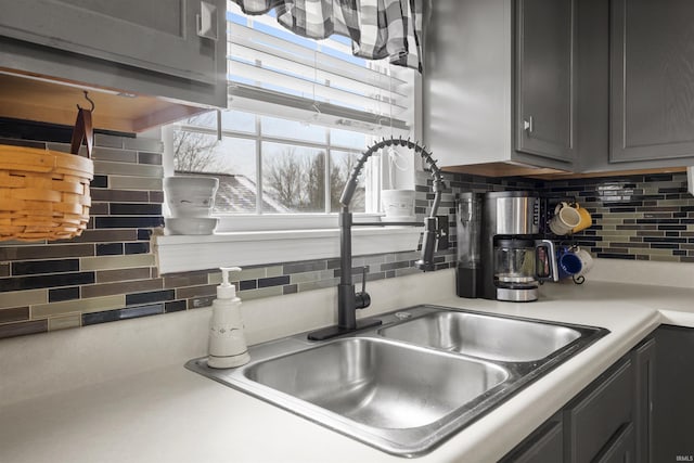 kitchen with tasteful backsplash, gray cabinetry, and sink