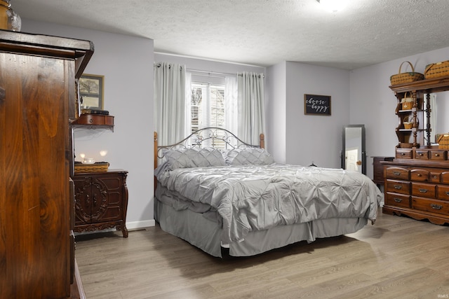 bedroom with light hardwood / wood-style floors and a textured ceiling