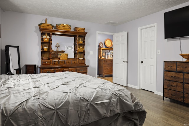 bedroom with hardwood / wood-style floors and a textured ceiling