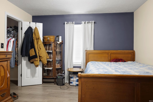 bedroom featuring a textured ceiling, light hardwood / wood-style floors, and a closet