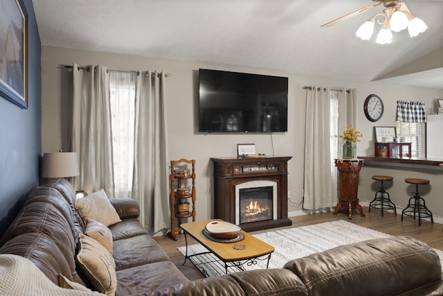 living room with ceiling fan, wood-type flooring, and vaulted ceiling