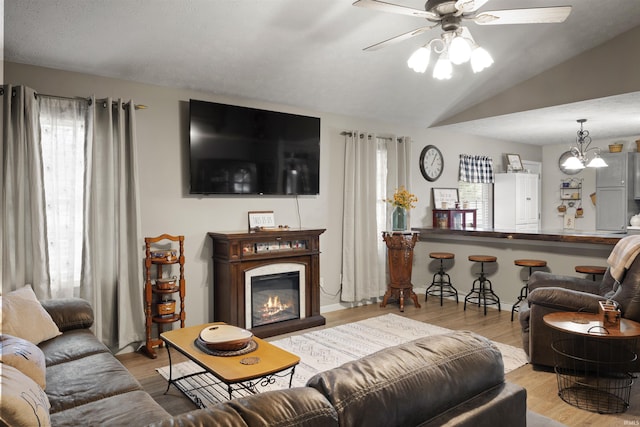 living room with lofted ceiling, a wealth of natural light, and light hardwood / wood-style flooring