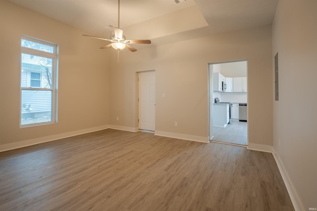 spare room with a raised ceiling, ceiling fan, and wood-type flooring