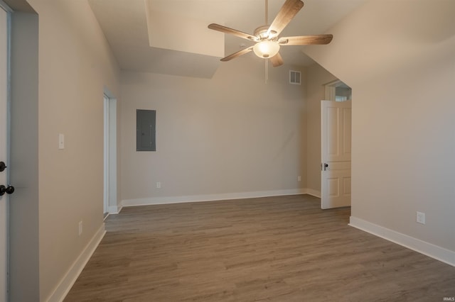 empty room featuring electric panel, ceiling fan, wood-type flooring, and vaulted ceiling