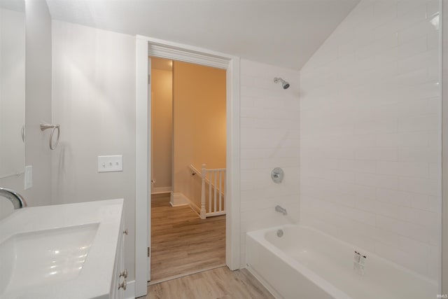 bathroom featuring vanity, tiled shower / bath combo, hardwood / wood-style flooring, and lofted ceiling