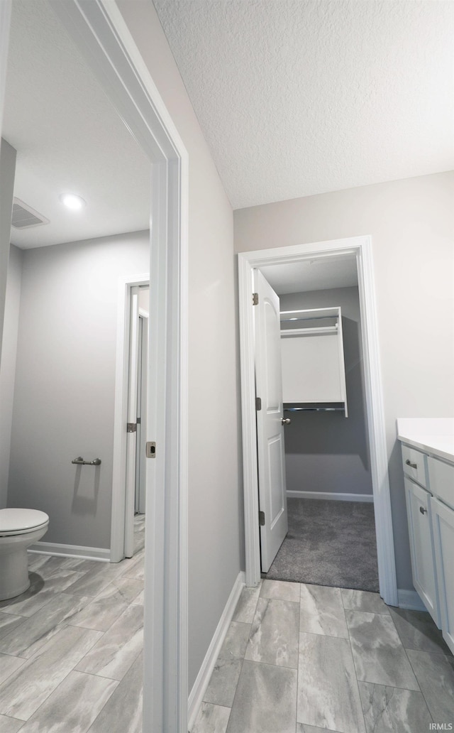 bathroom with vanity, toilet, and a textured ceiling