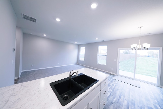 kitchen featuring carpet, white cabinets, sink, decorative light fixtures, and a chandelier