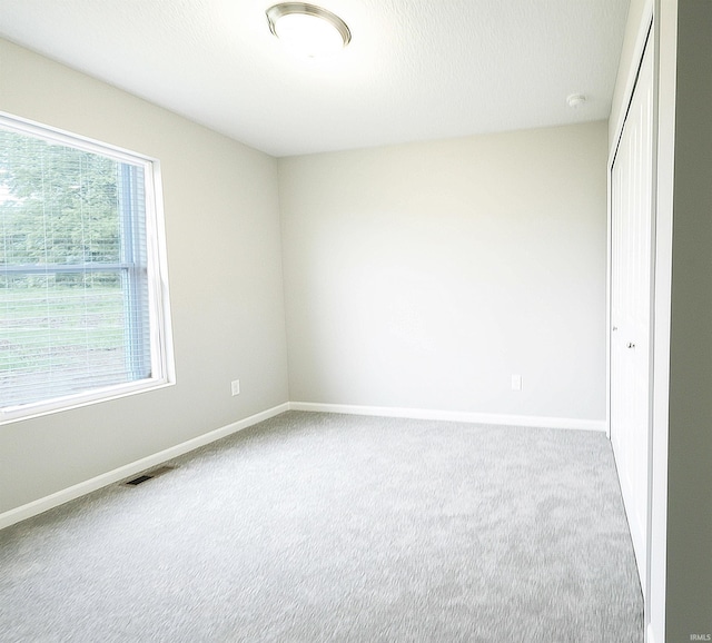 unfurnished bedroom with light colored carpet and a closet