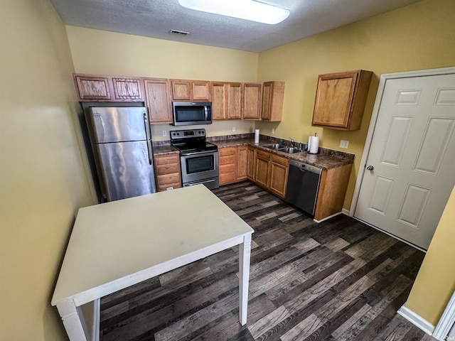 kitchen with a textured ceiling, sink, stainless steel appliances, and dark hardwood / wood-style floors