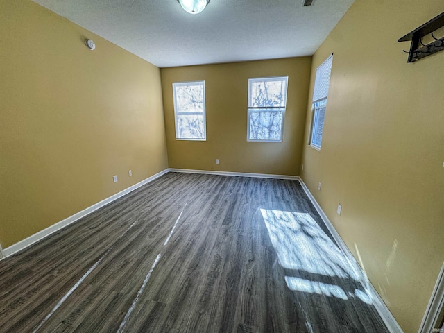 empty room with dark wood-type flooring and a textured ceiling