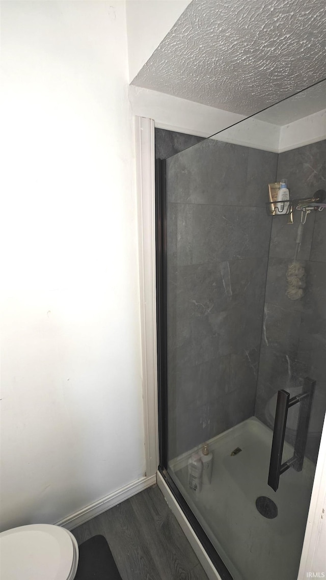 bathroom with tiled shower, wood-type flooring, and toilet