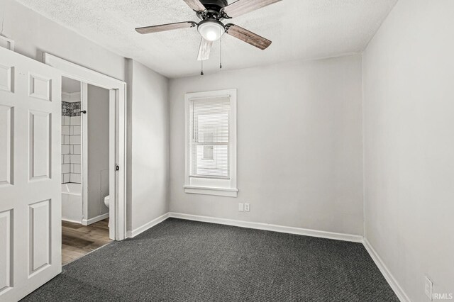 unfurnished bedroom with ensuite bath, ceiling fan, a textured ceiling, a closet, and dark carpet